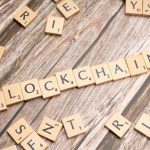 Peças de madeira formam a palavra “blockchain” sobre uma superfície de madeira.