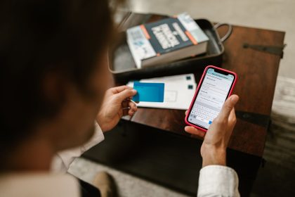 Pessoa realiza um pagamento digital pelo celular enquanto segura um cartão, em ambiente interno.