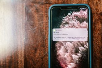 Smartphone exibindo uma notificação de alerta de fraude sobre uma superfície de madeira.